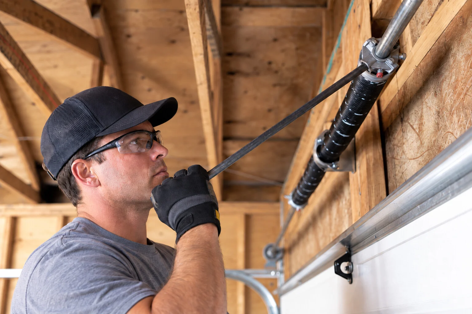 Technician replacing a torsion spring above a residential door