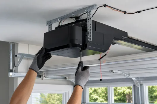 Technician installing a ceiling-mounted garage door opener