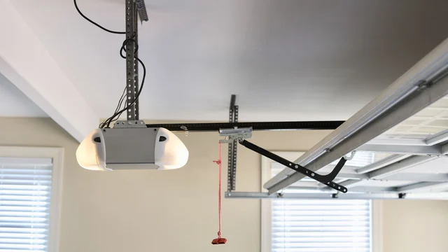 Ceiling-mounted garage door opener with its rail, door arm and red emergency release cord