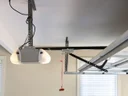 Ceiling-mounted garage door opener with its rail, door arm and red emergency release cord