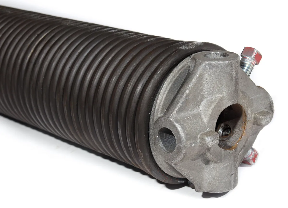 Technician tightening torsion springs on a residential garage door